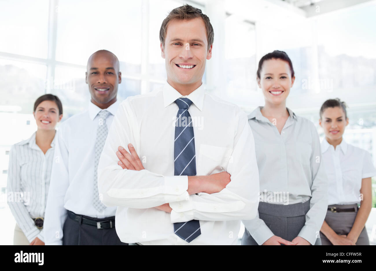 Smiling businessman with arms crossed and his team Stock Photo