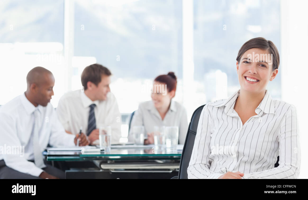 Smiling tradeswoman with meeting being held behind her Stock Photo
