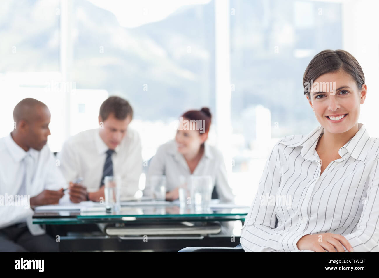 Smiling businesswoman with colleagues behind her holding a meeting Stock Photo