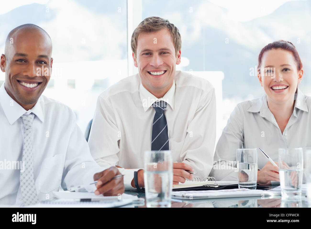 Smiling businesspeople sitting together at a table Stock Photo