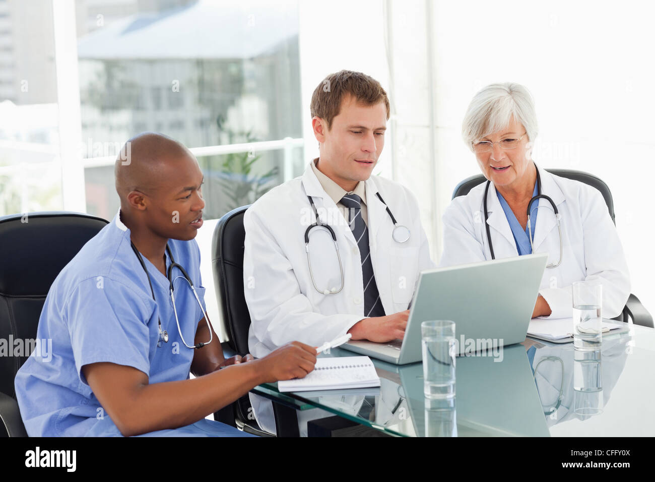 Doctors sitting in meeting room with a laptop Stock Photo