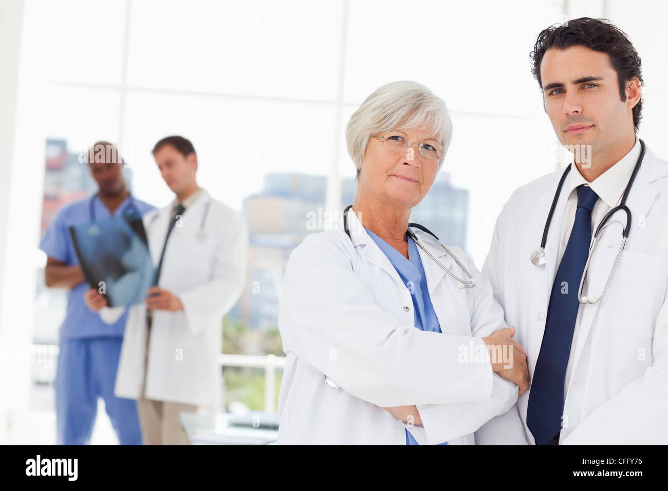 Confident doctors with colleagues behind them Stock Photo