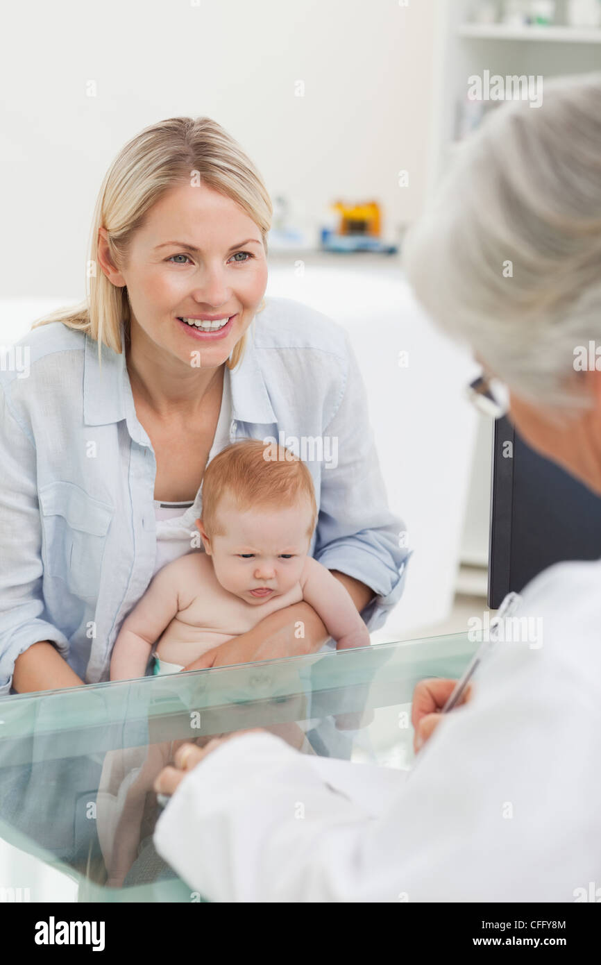 Smiling mother with her baby seeing the doctor Stock Photo - Alamy