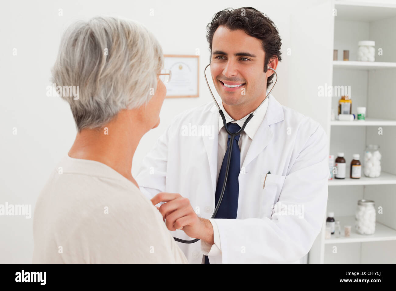 Smiling doctor taking mature patients heart beat Stock Photo