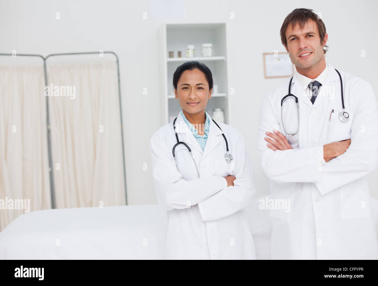 Smiling doctors crossing their arms while standing in a hospital room Stock Photo