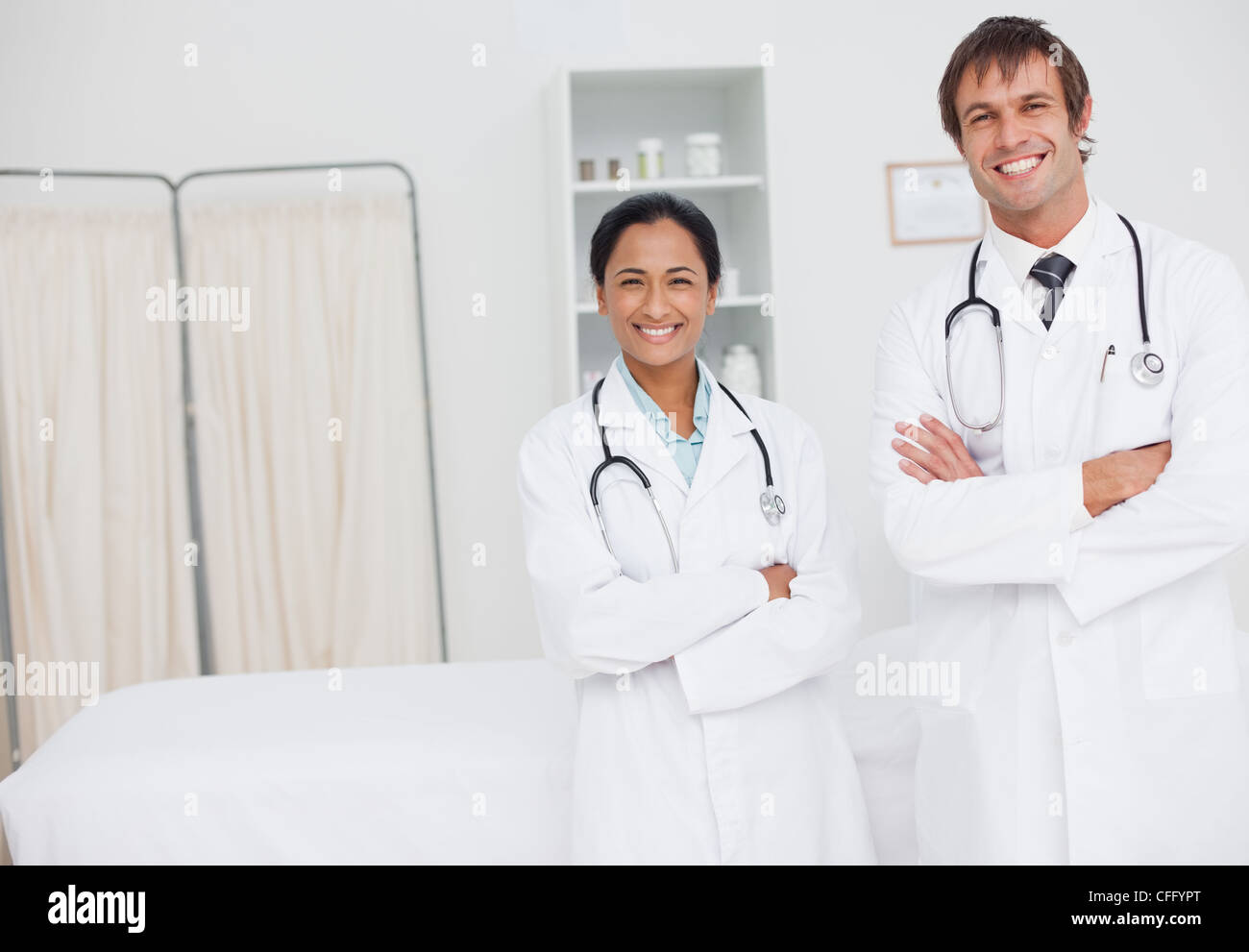 Young happy surgeons standing in a hospital room while crossing their arms Stock Photo
