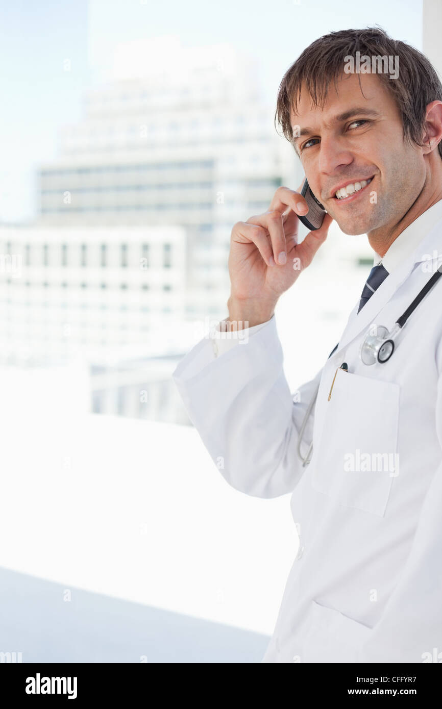 Smiling doctor looking at the camera while talking on the phone Stock Photo
