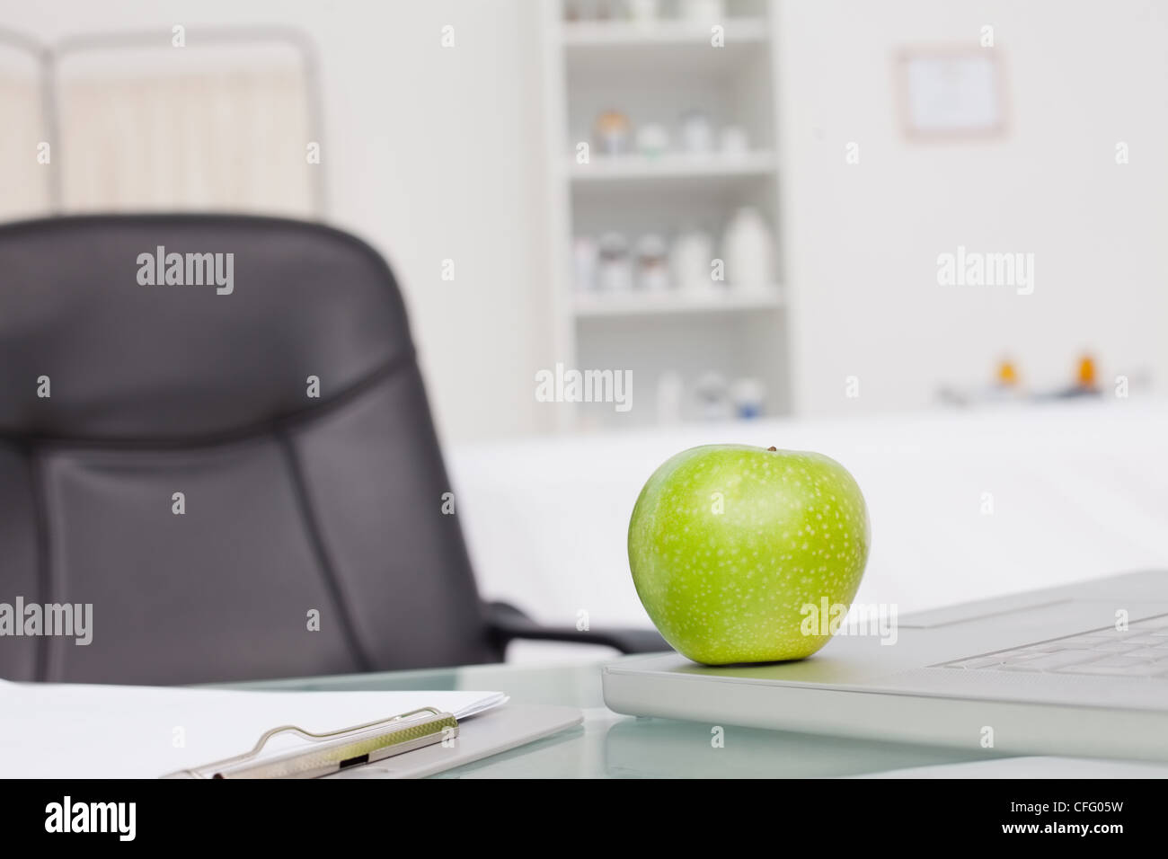 Green apple placed on a laptop near a clipboard Stock Photo