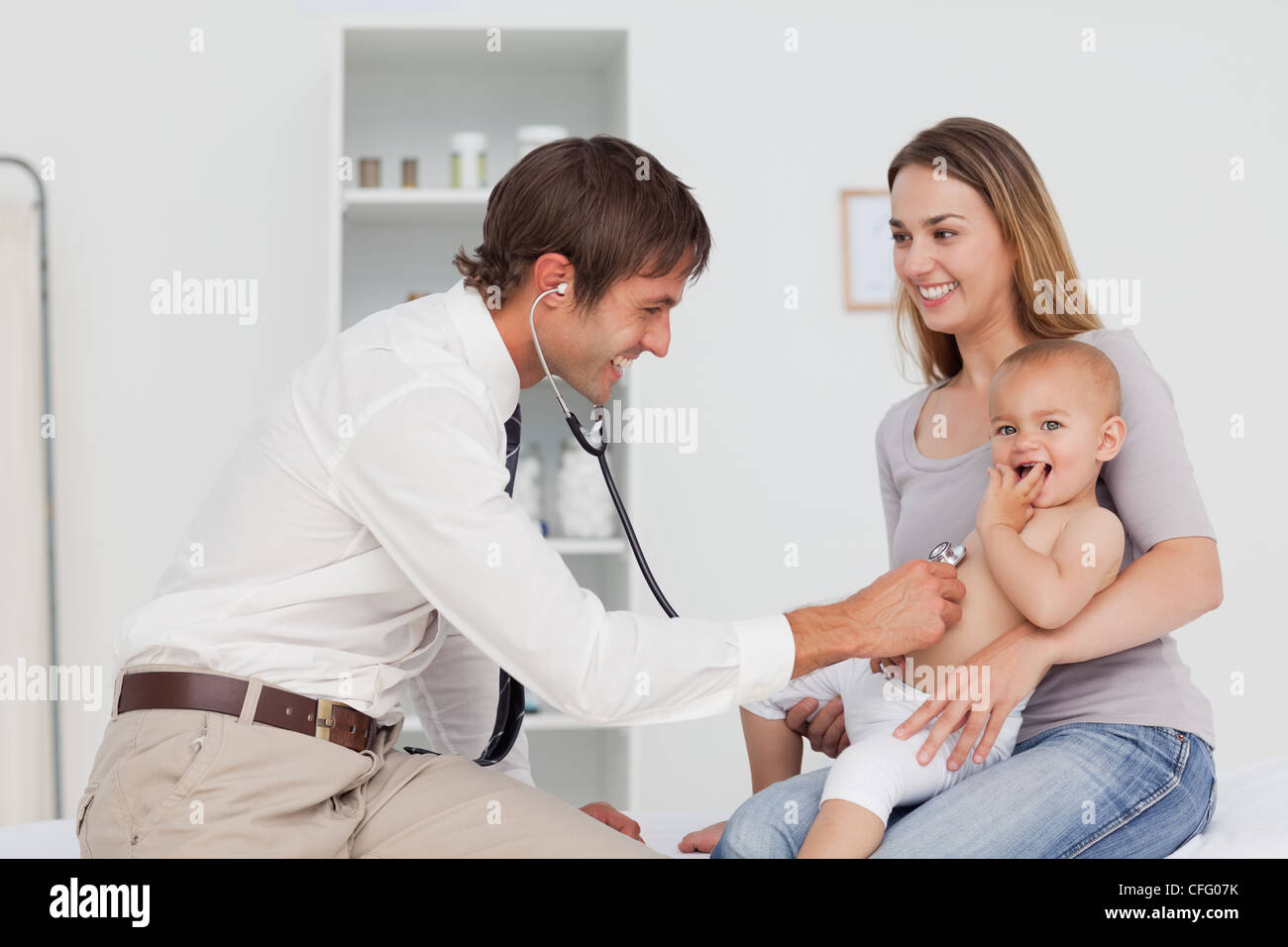 Smiling mother looking at the doctor while holding her baby Stock Photo ...