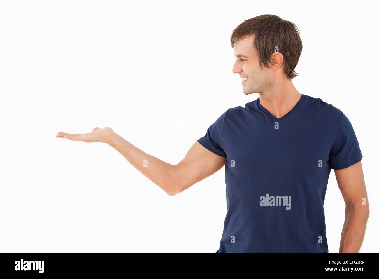 Smiling man standing upright with hand palm up Stock Photo