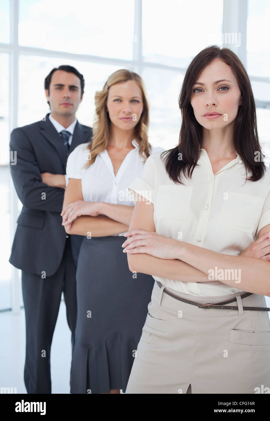 Three colleagues standing seriously behind each other with their arms crossed Stock Photo