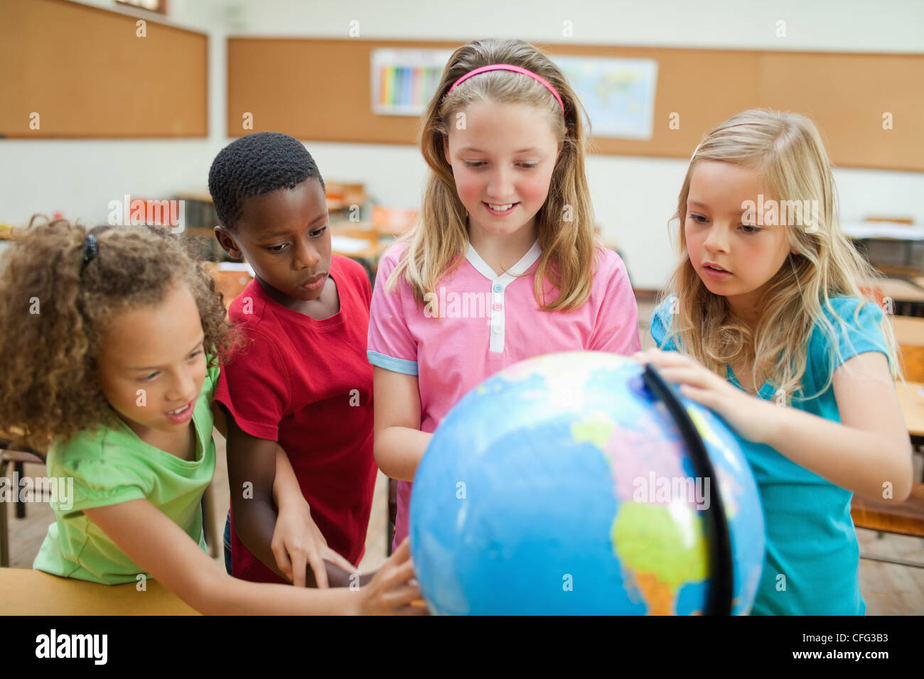 Students exploring globe together Stock Photo