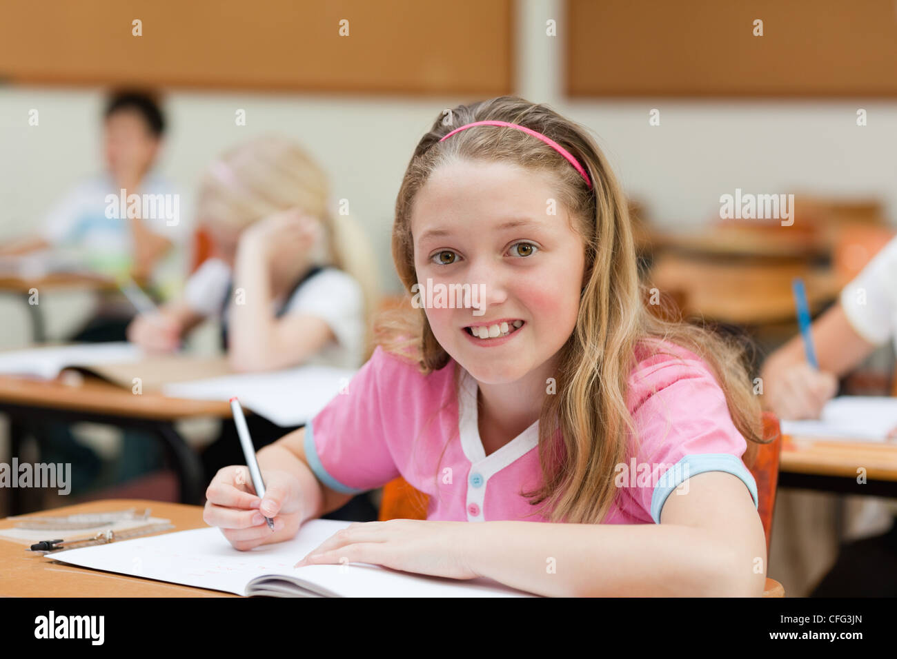 Smiling female schoolchild at her desk Stock Photo