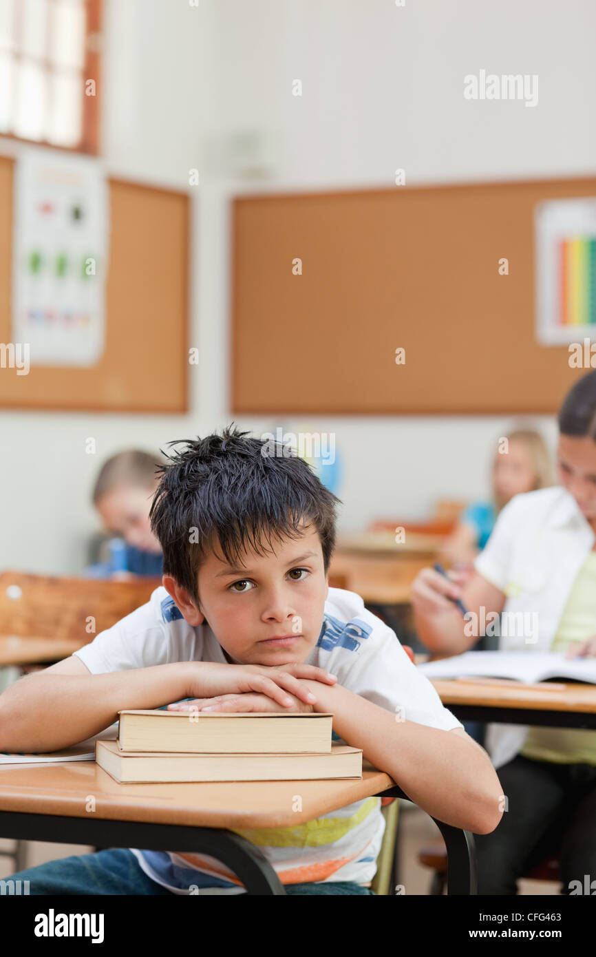 Sad looking student leaning on a pile of books Stock Photo - Alamy