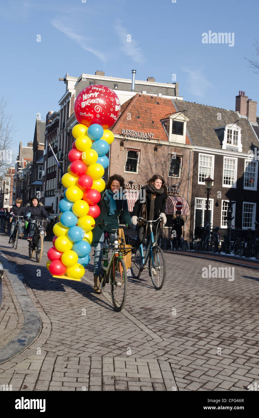 Lady traveling in Amsterdam on a bike carrying balloons. Stock Photo