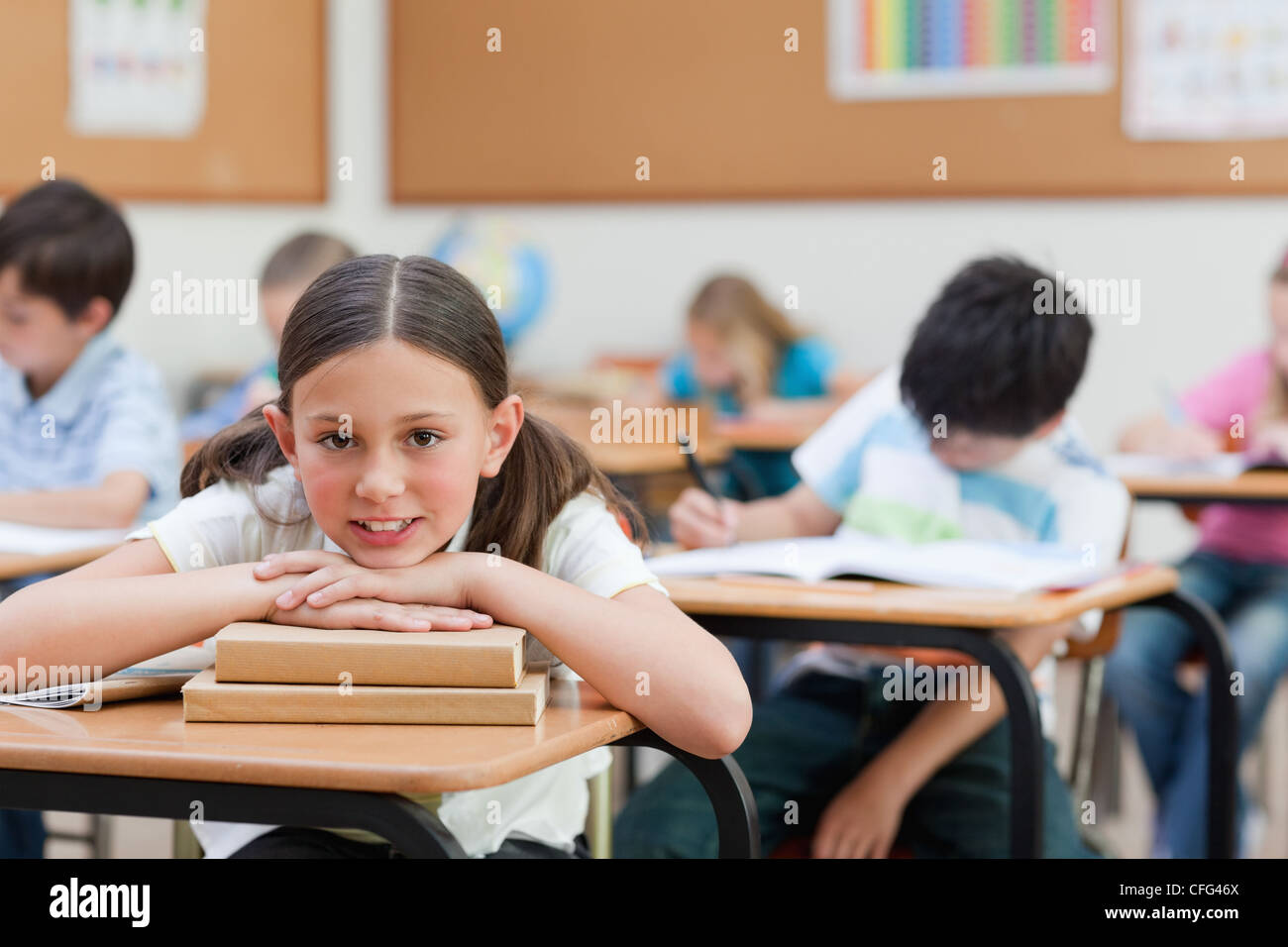 Smiling schoolgirl leaning on pile of books Stock Photo - Alamy