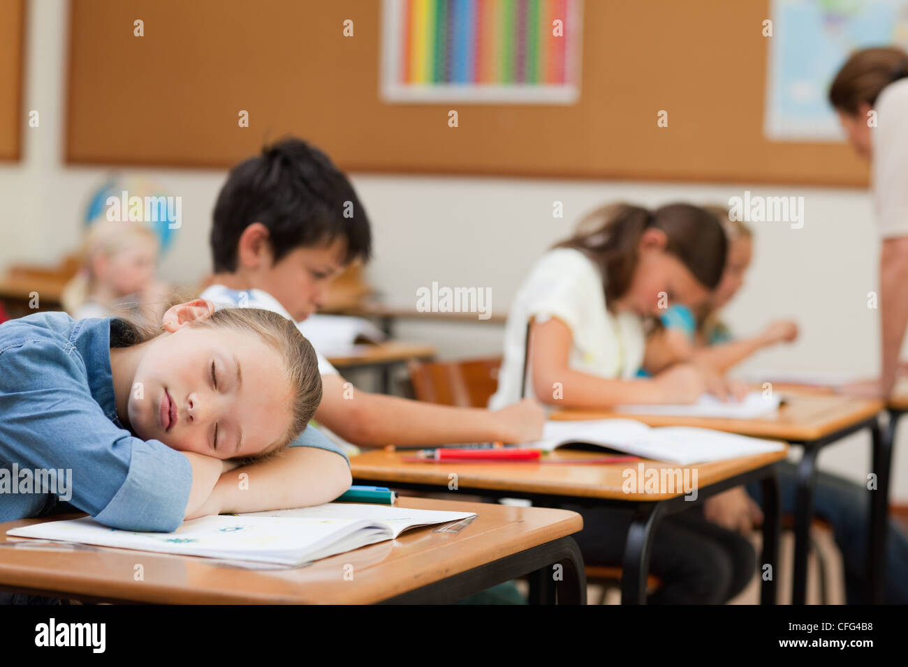 Side view of schoolgirl sleeping at desk Stock Photo