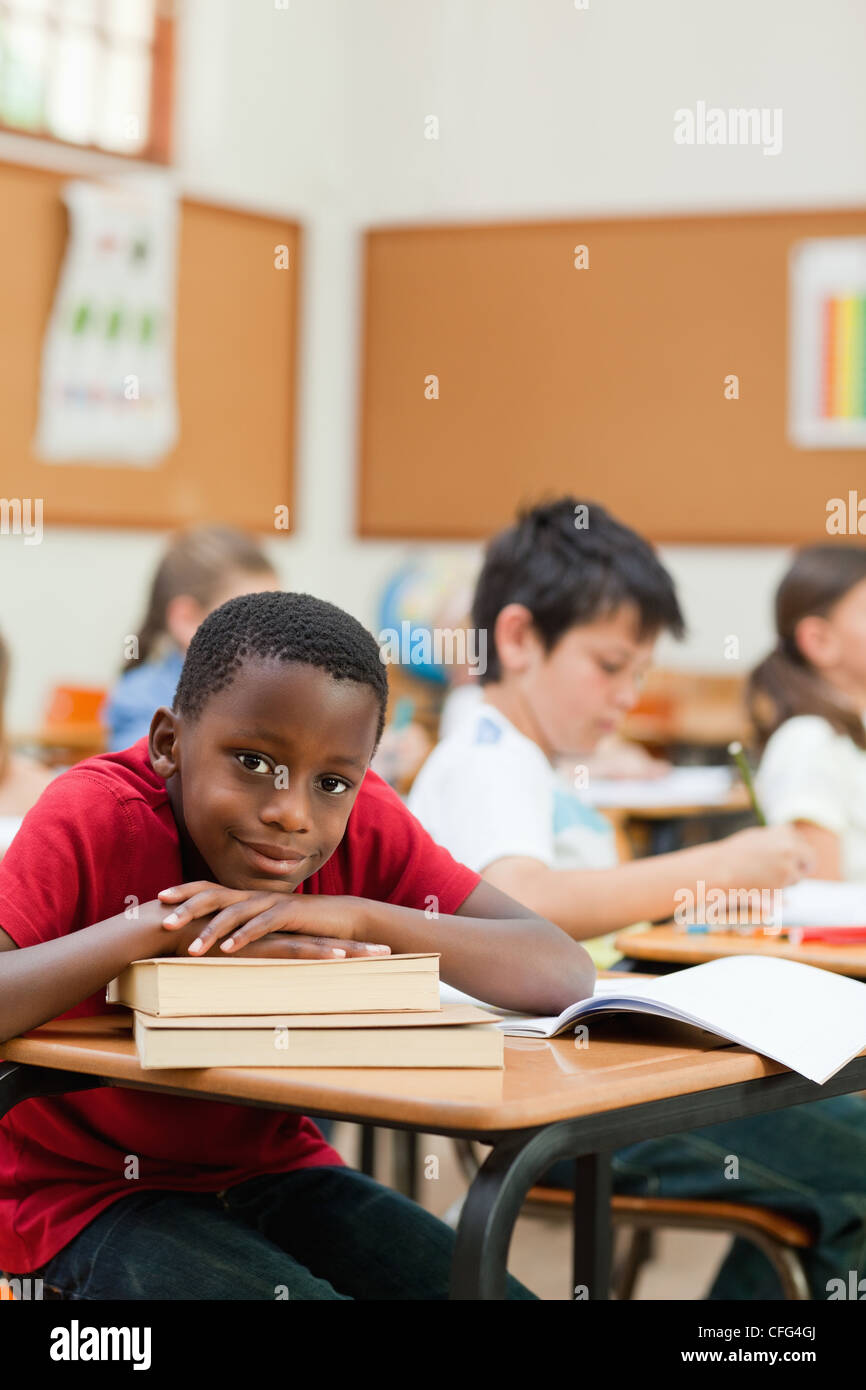 Smiling student leaning on a stack of books Stock Photo - Alamy