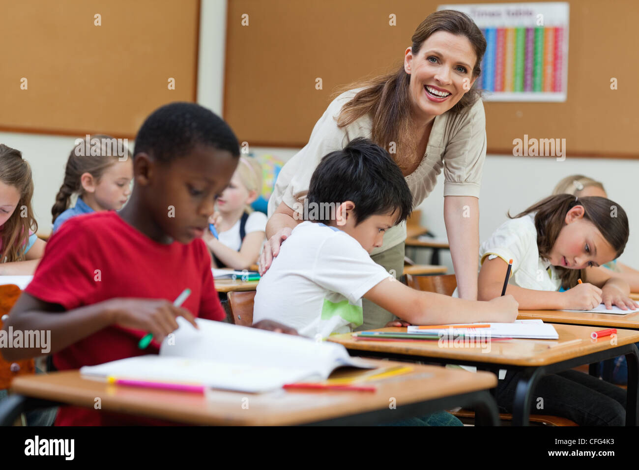 Side view of smiling teacher helping her students Stock Photo - Alamy