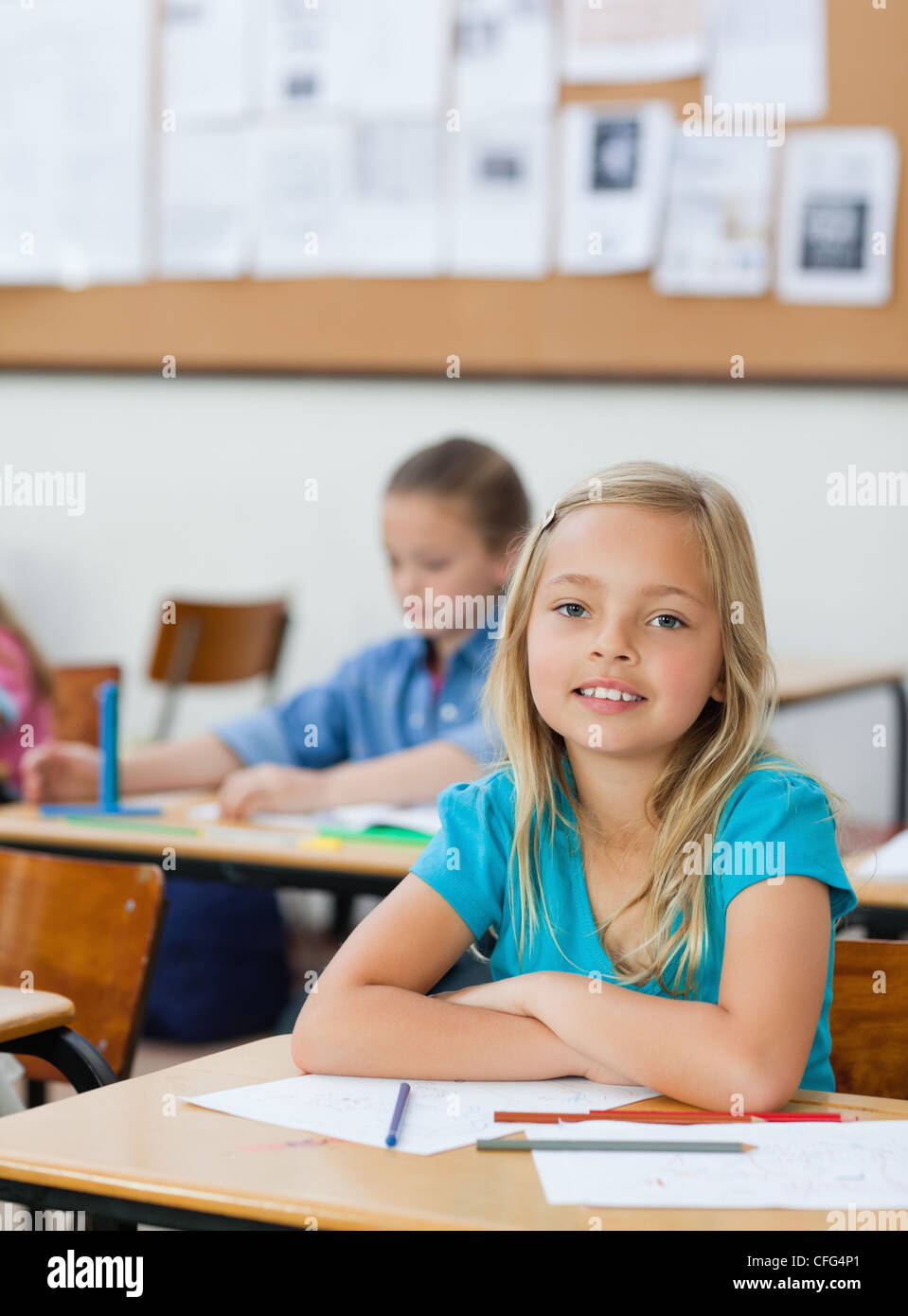 Student sitting at her desk with arms folded Stock Photo