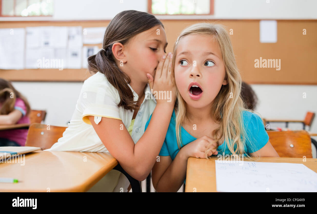 Schoolgirl telling her schoolfellow a secret Stock Photo