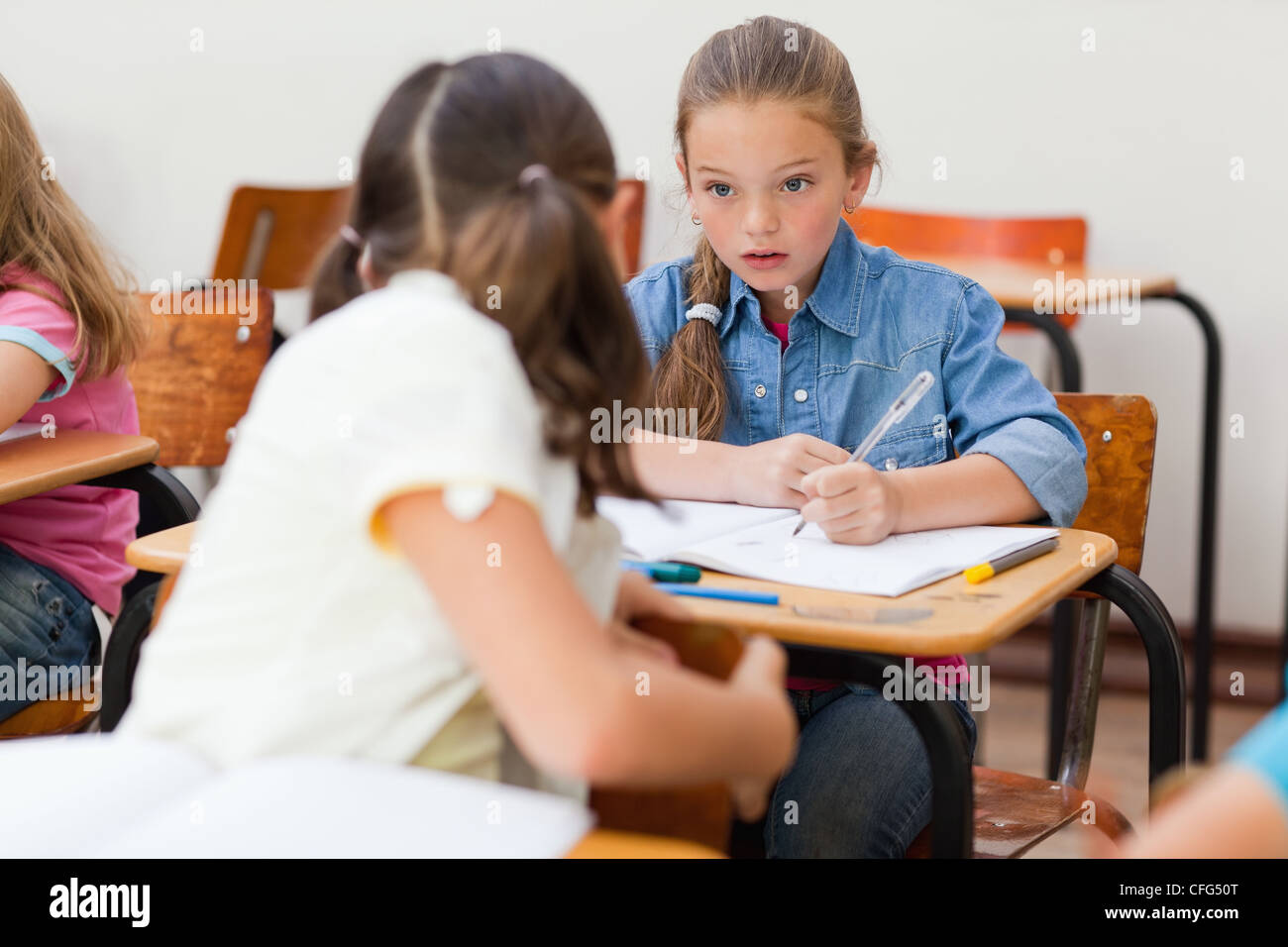 Girl helping schoolfellow in class Stock Photo