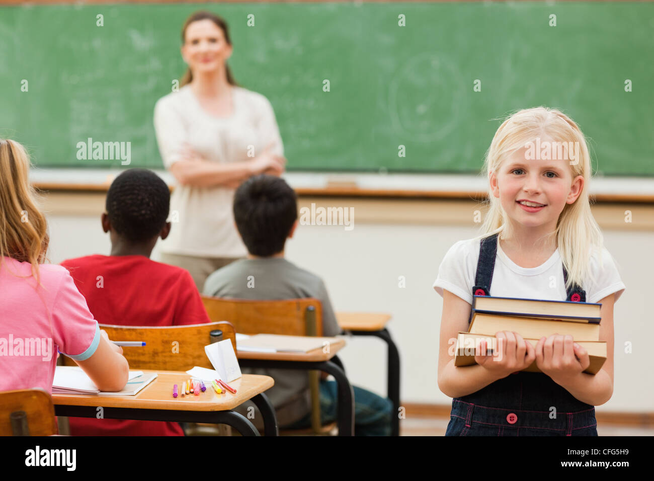 Girl holding stack of books in class Stock Photo - Alamy