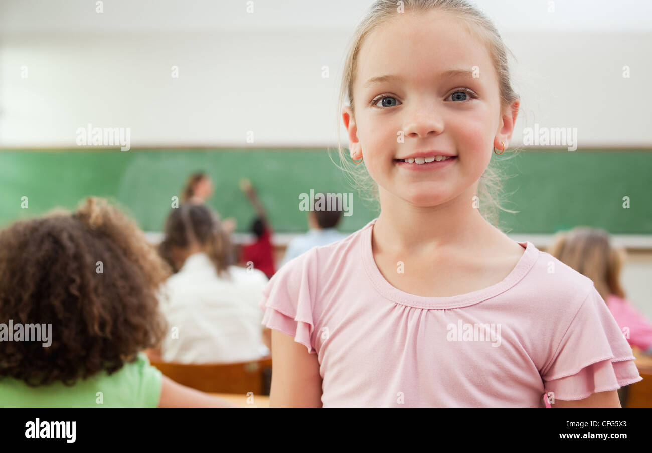 Smiling schoolgirl standing in classroom Stock Photo