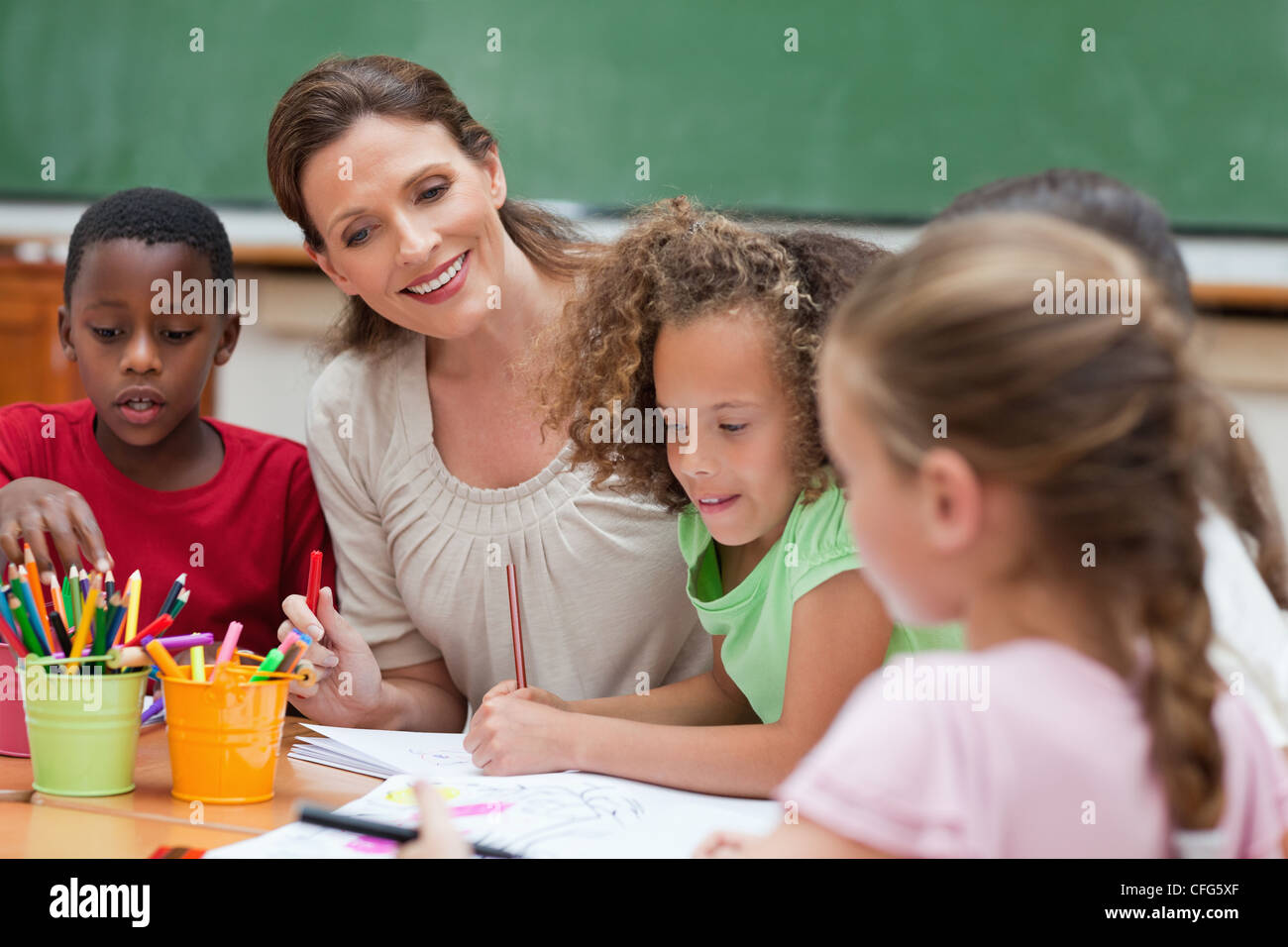 Smiling teacher painting together with students Stock Photo - Alamy