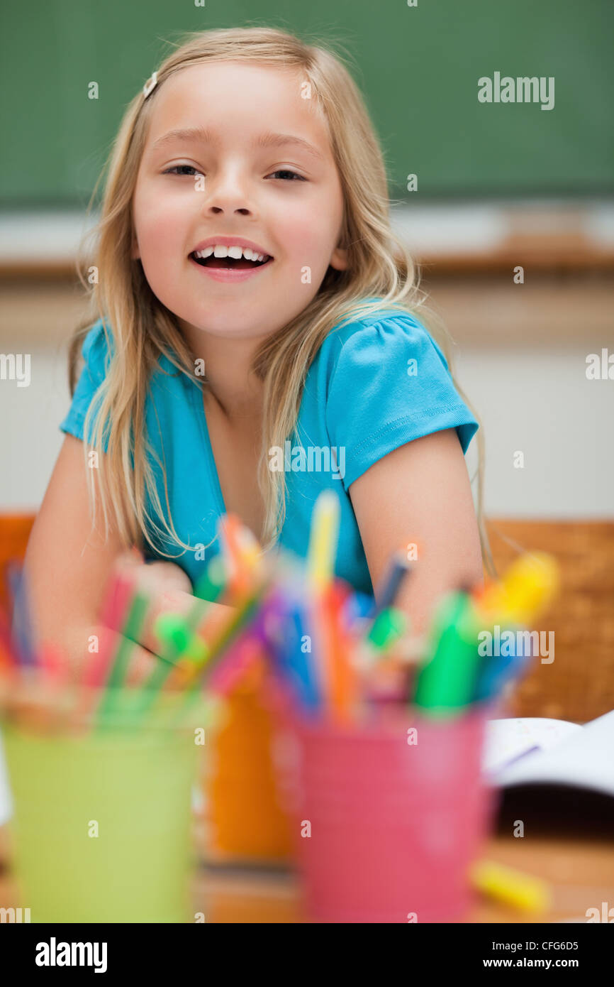 Smiling student sitting next to pencil holders Stock Photo