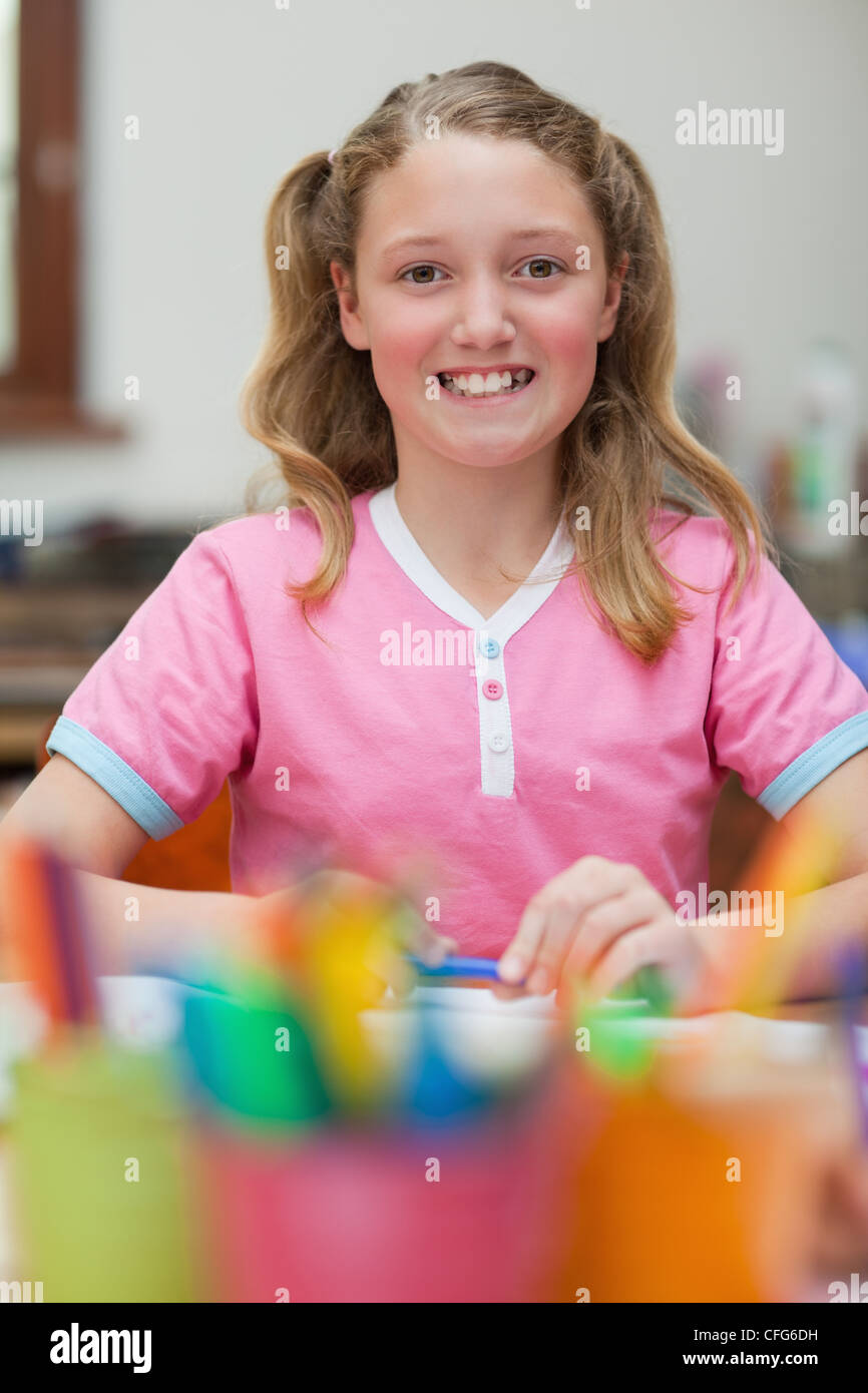 Smiling girl sitting at desk during art class Stock Photo