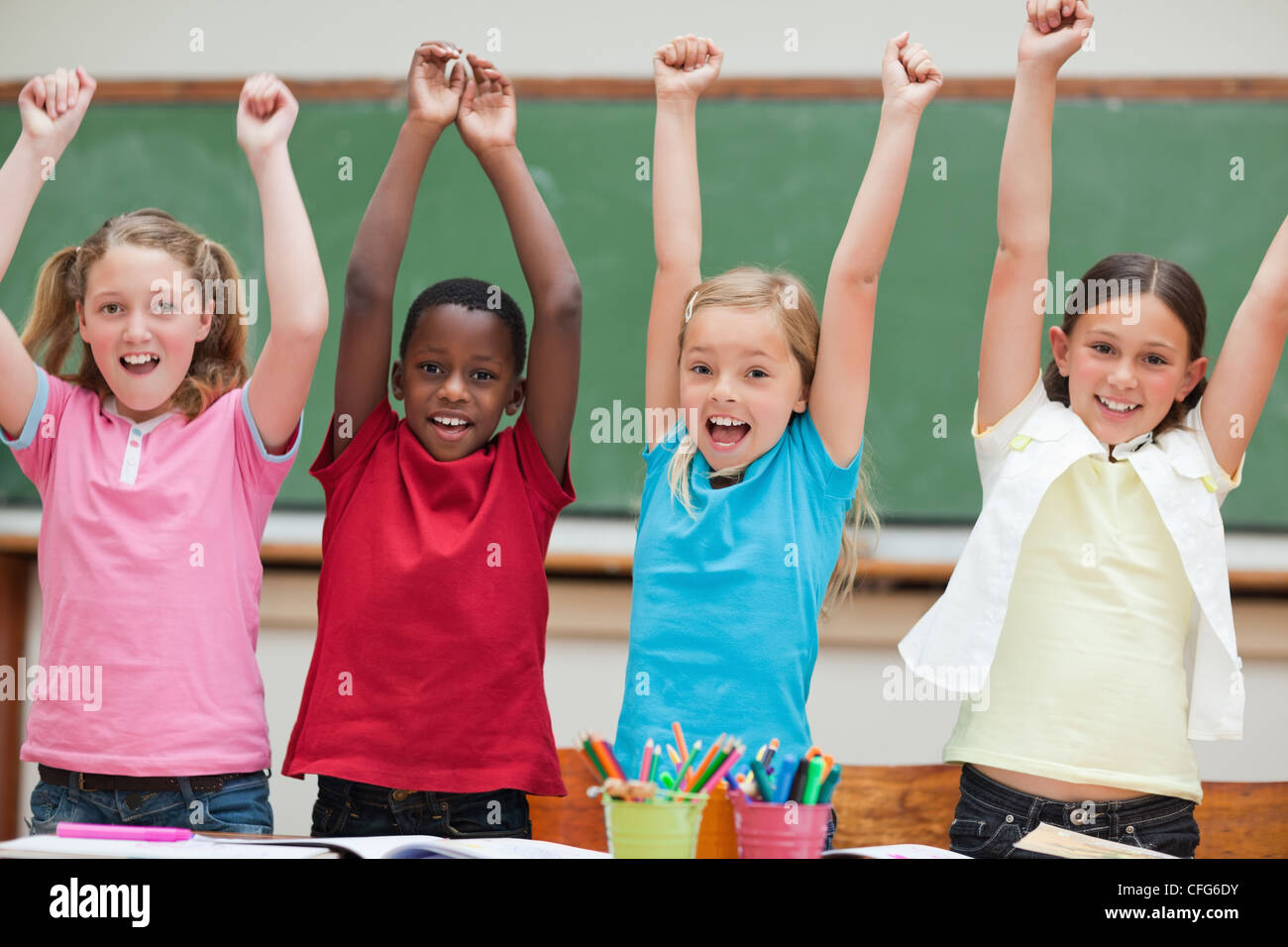 Cheering students standing in classroom Stock Photo