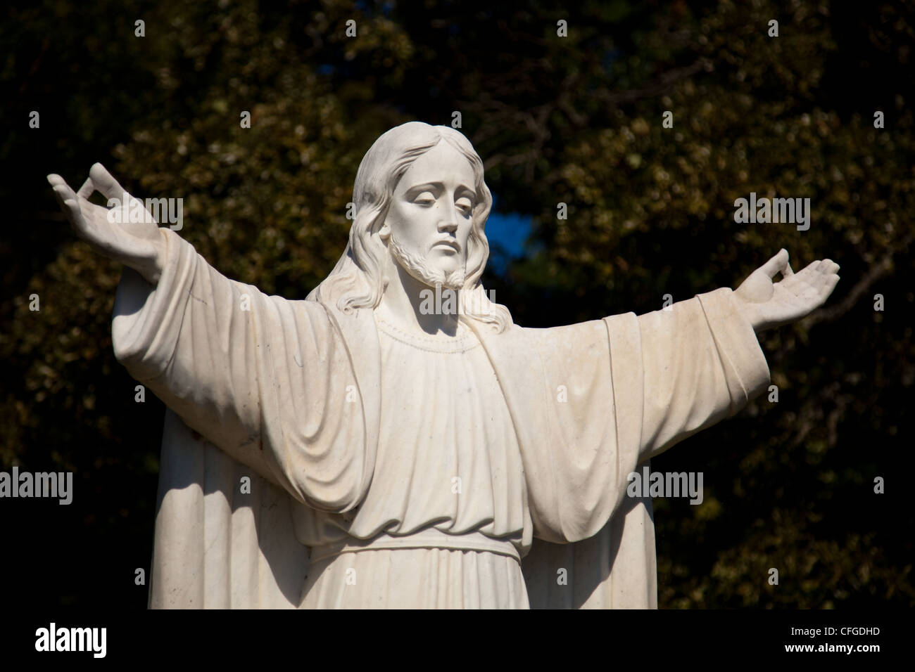 Statue of Jesus with outstretched arms in an outdoor garden Stock Photo