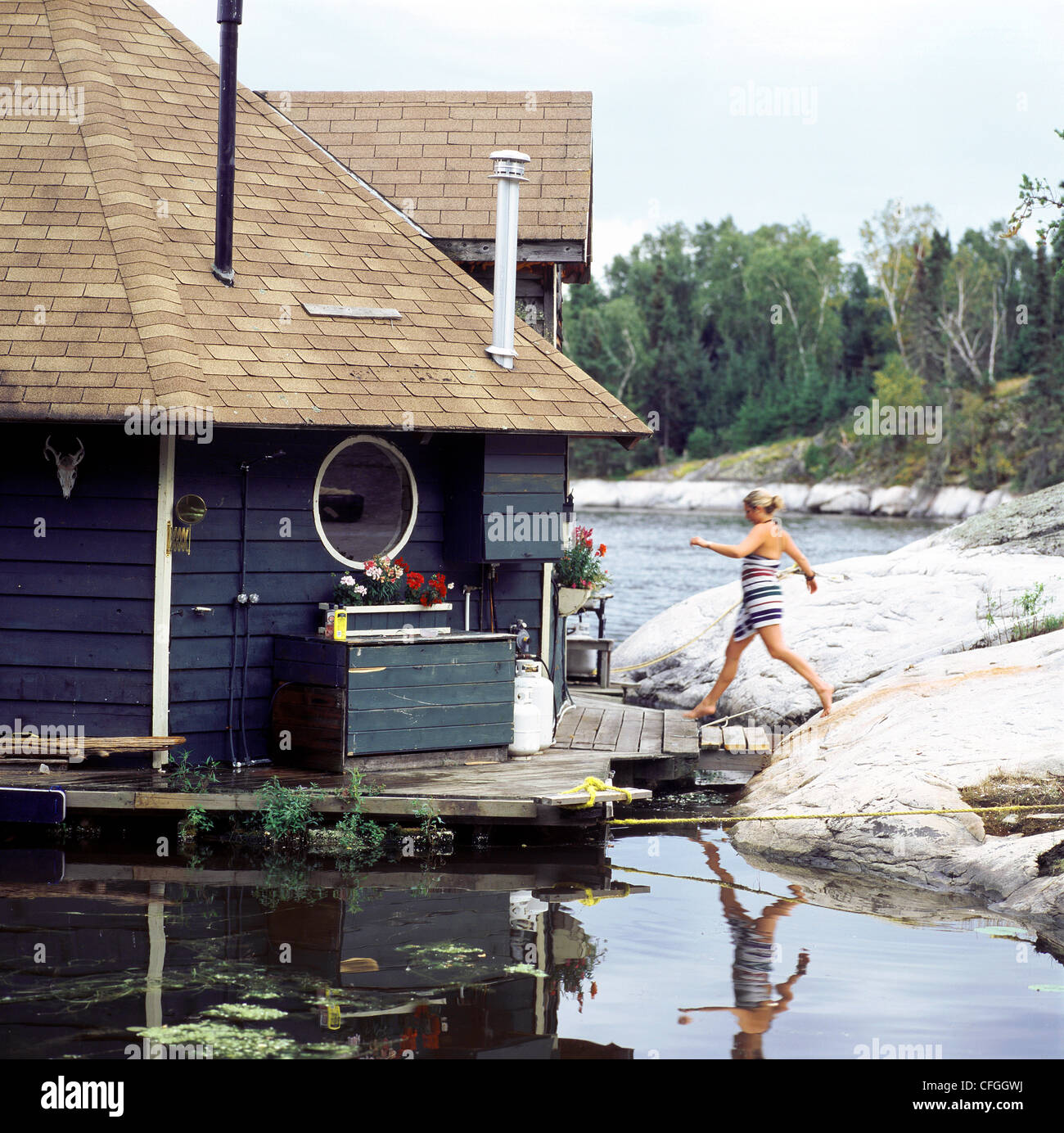 Young Woman Jumping towards Cottage Doorway, Gunn Lake, Minaki, Ontario