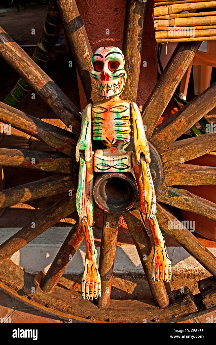 Day of the Dead skeleton puppet against a wagon wheel in front of a restaurant in downtown Zihuatanejo, Mexico Stock Photo