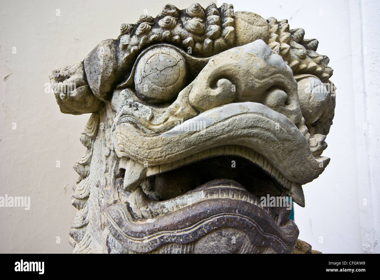 A stone statue of a fearsome lions head displaying sharp canine teeth. Stock Photo