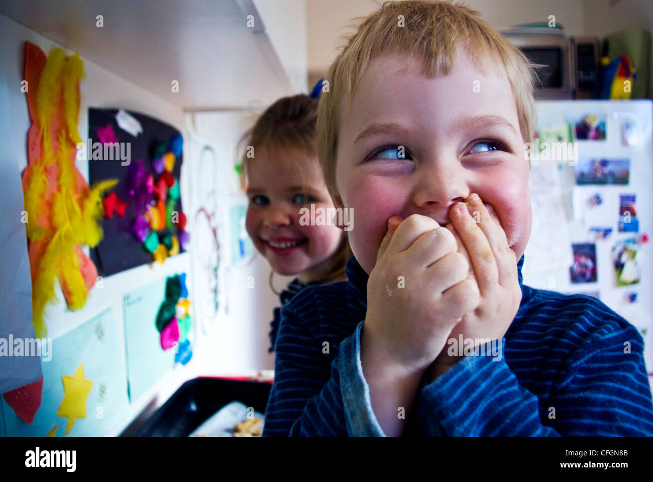 A cheeky boy caught stealing chocolate whilst baking gingerbread men. Stock Photo