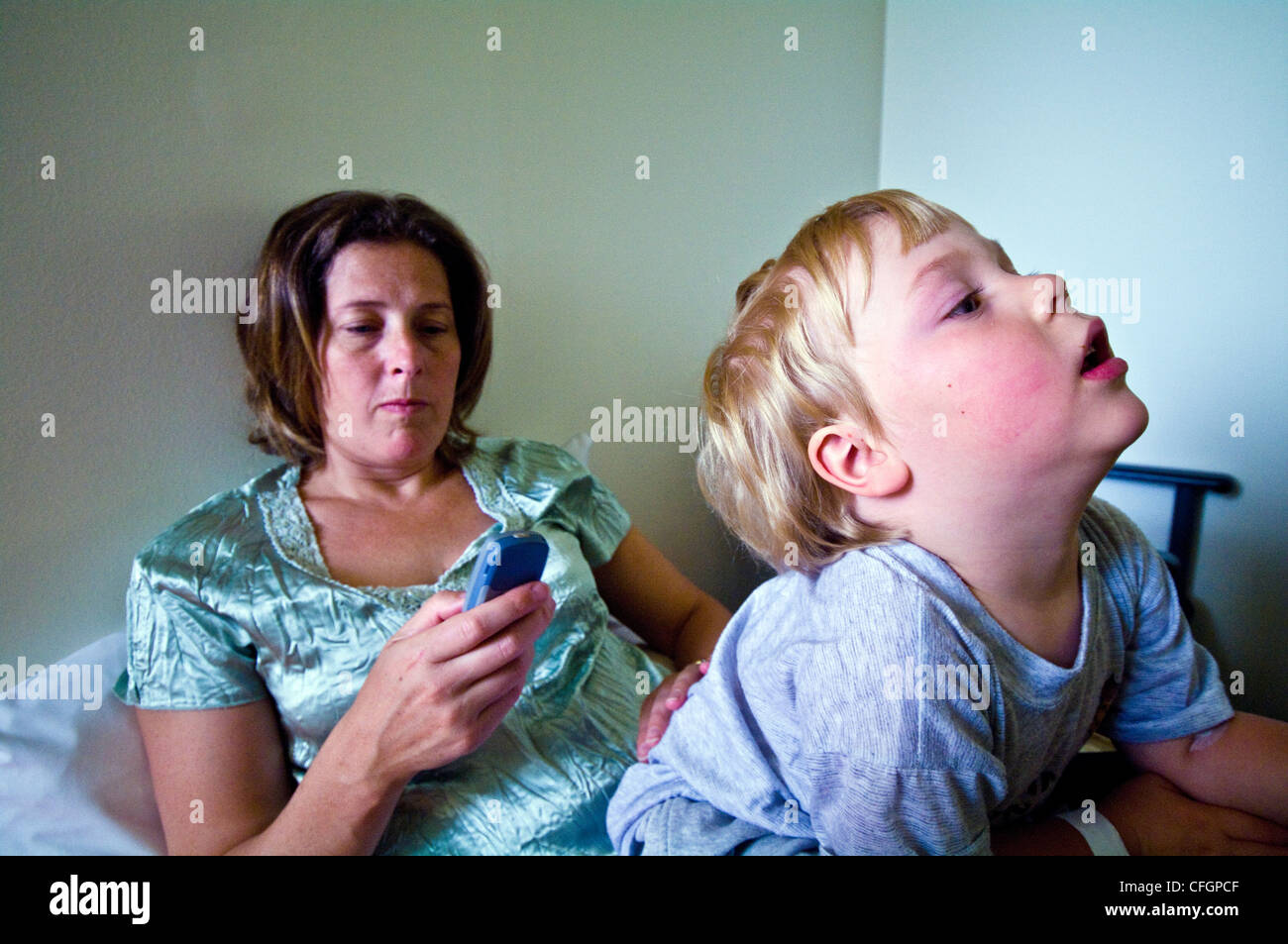 A mother sends a message on her cell phone in a hospital waiting room. Stock Photo