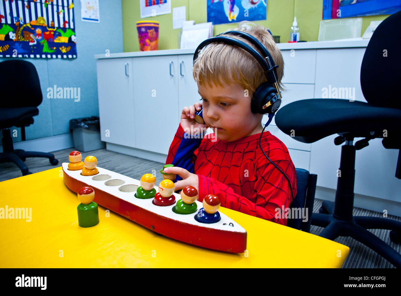 A boy undergoes a clinical hearing test using headphones and toys. Stock Photo