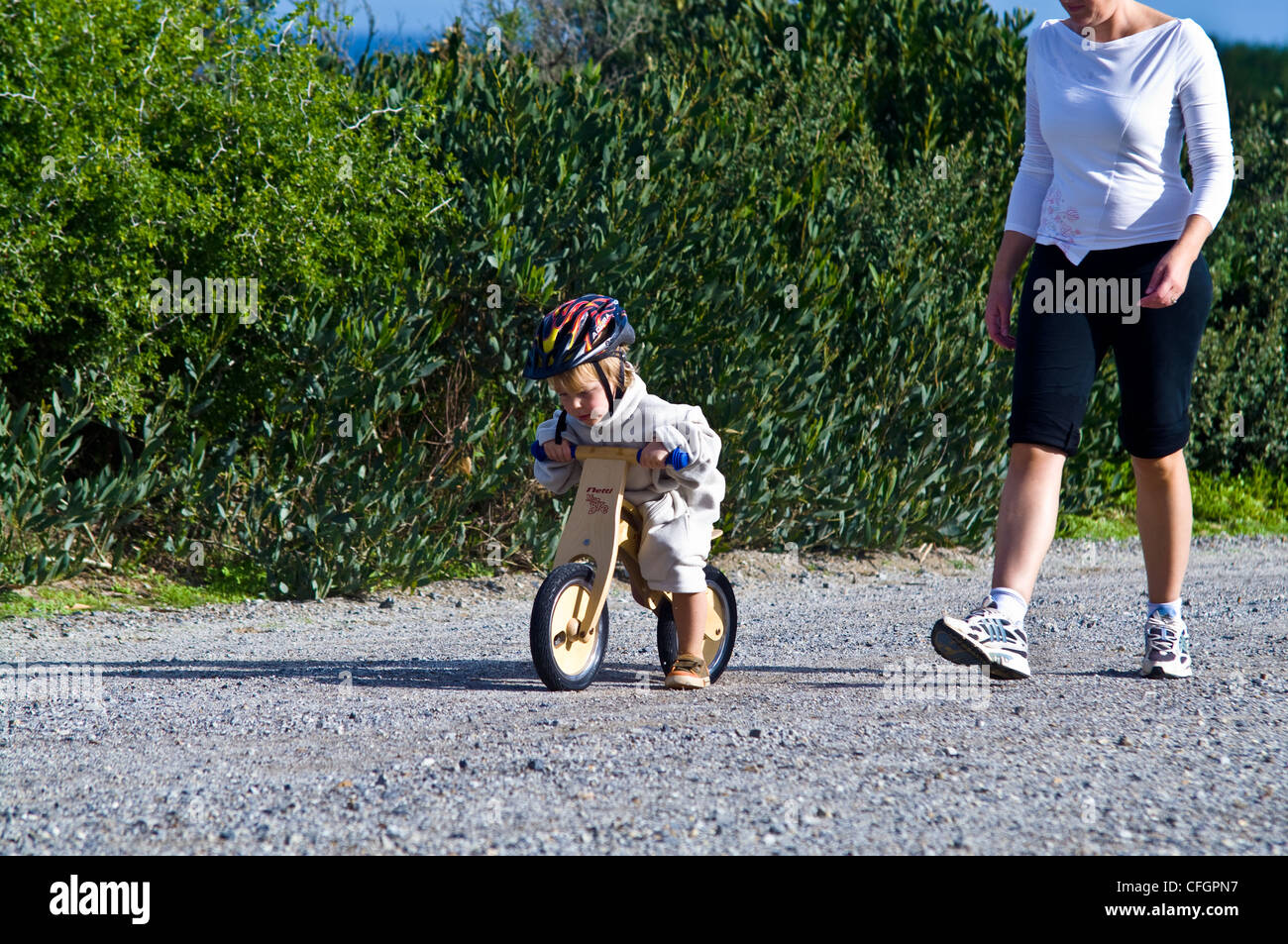 A young boy learns to ride a balance bike made from recycled timber. Stock Photo