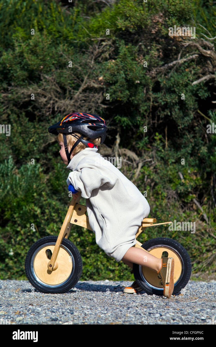 A young boy learns to ride a balance bike made from recycled timber. Stock Photo