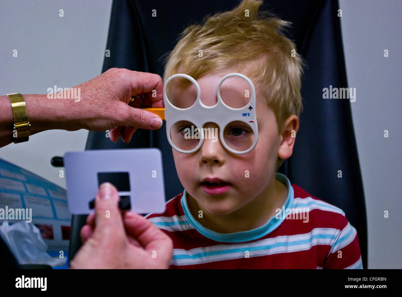 A children's optometrist gives a small boy his first eye examination