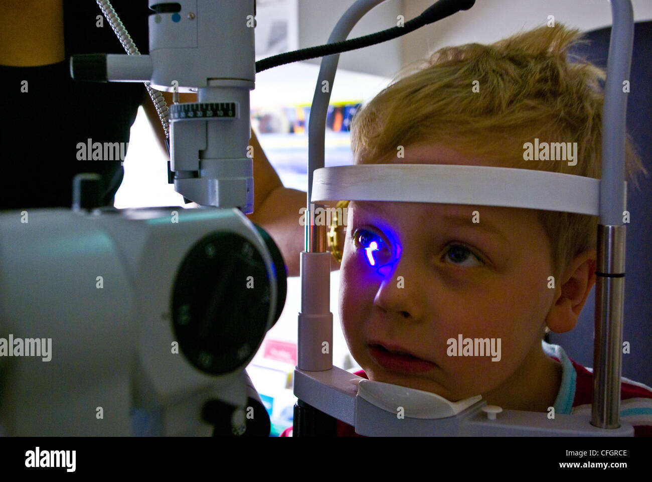 A children's optometrist gives a small boy his first eye examination