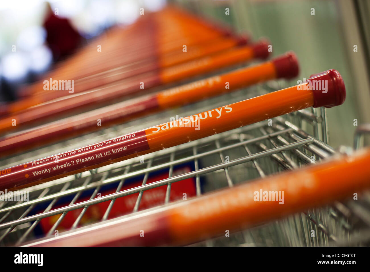 Sainsbury's shopping trolleys in a row showing the word Sainsbury's on the handles Stock Photo