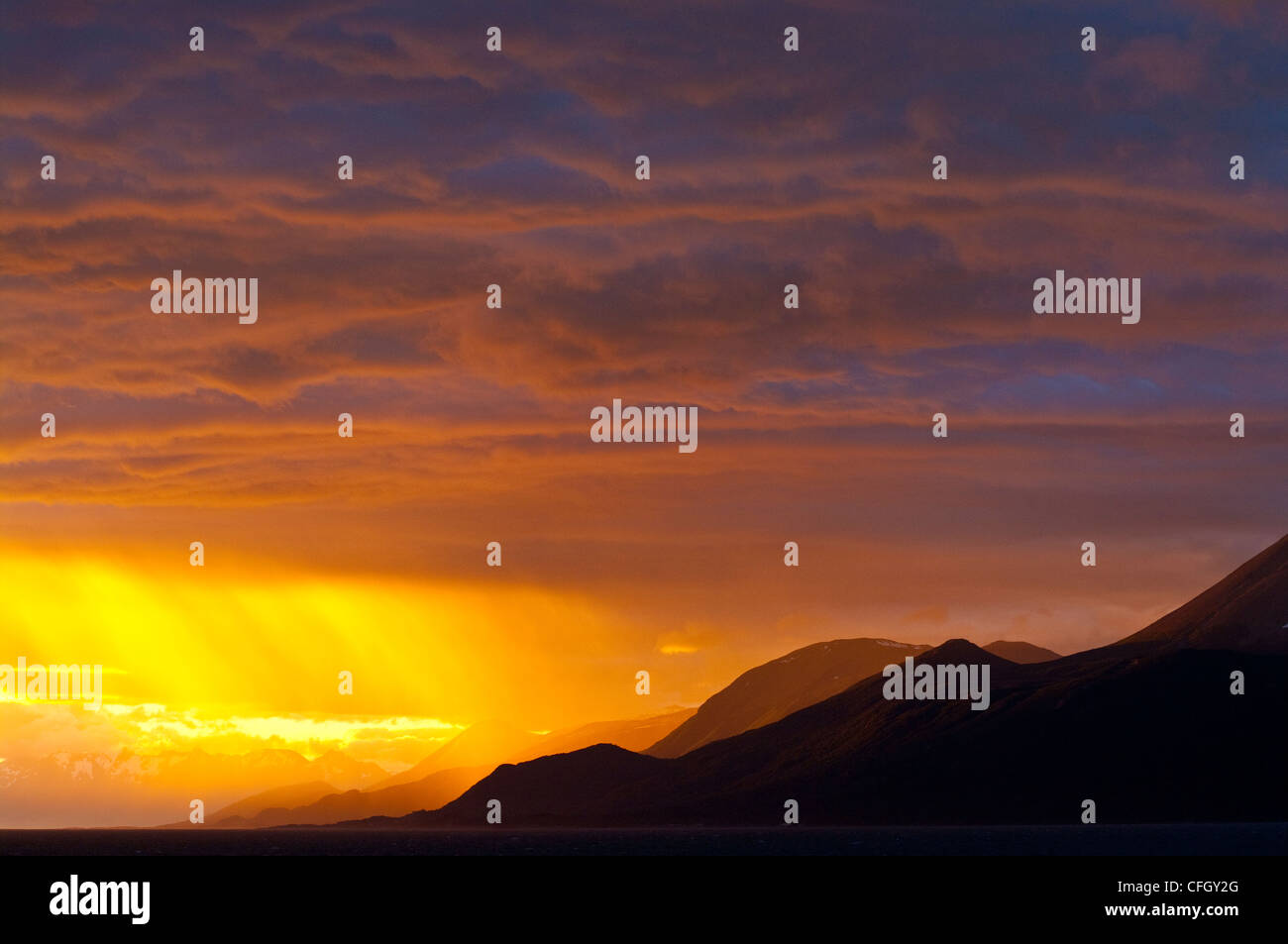 The setting sun turns a rain storm over the Andes fiery golden. Stock Photo
