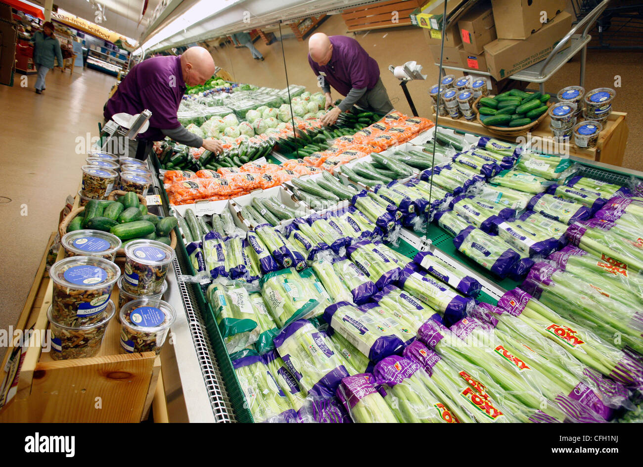 Supermarket employee stocking vegetables Stock Photo