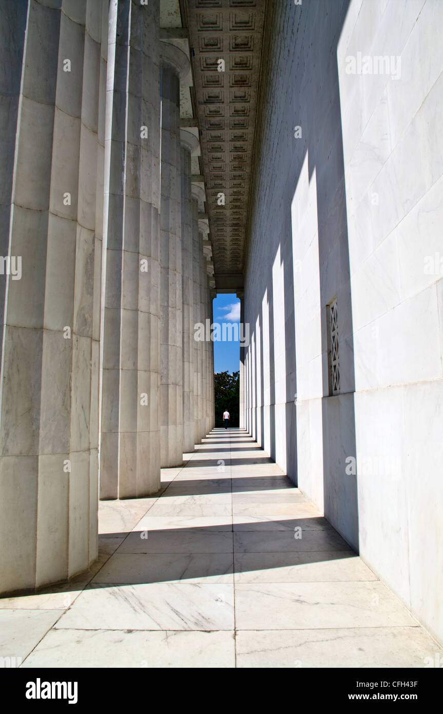 A tourist walks between marble Doric columns at the Lincoln Memorial. Stock Photo