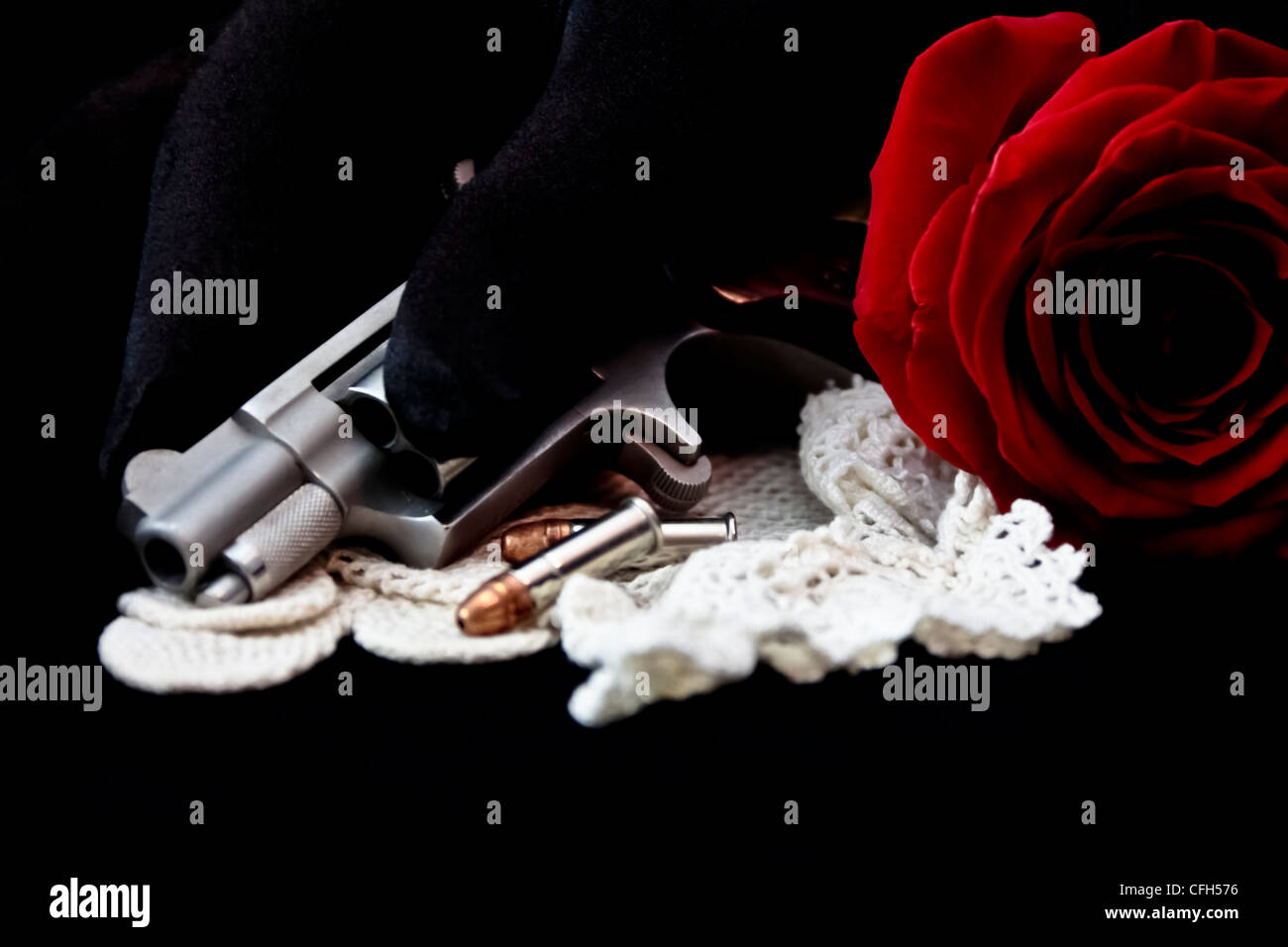 hand on gun with rose and bullets Stock Photo