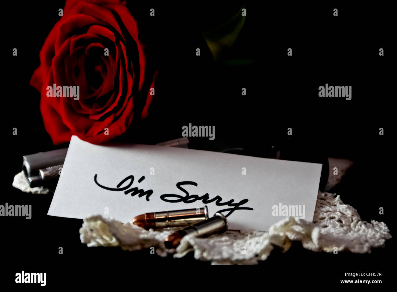 Red rose on black velvet with handgun and sorry note Stock Photo