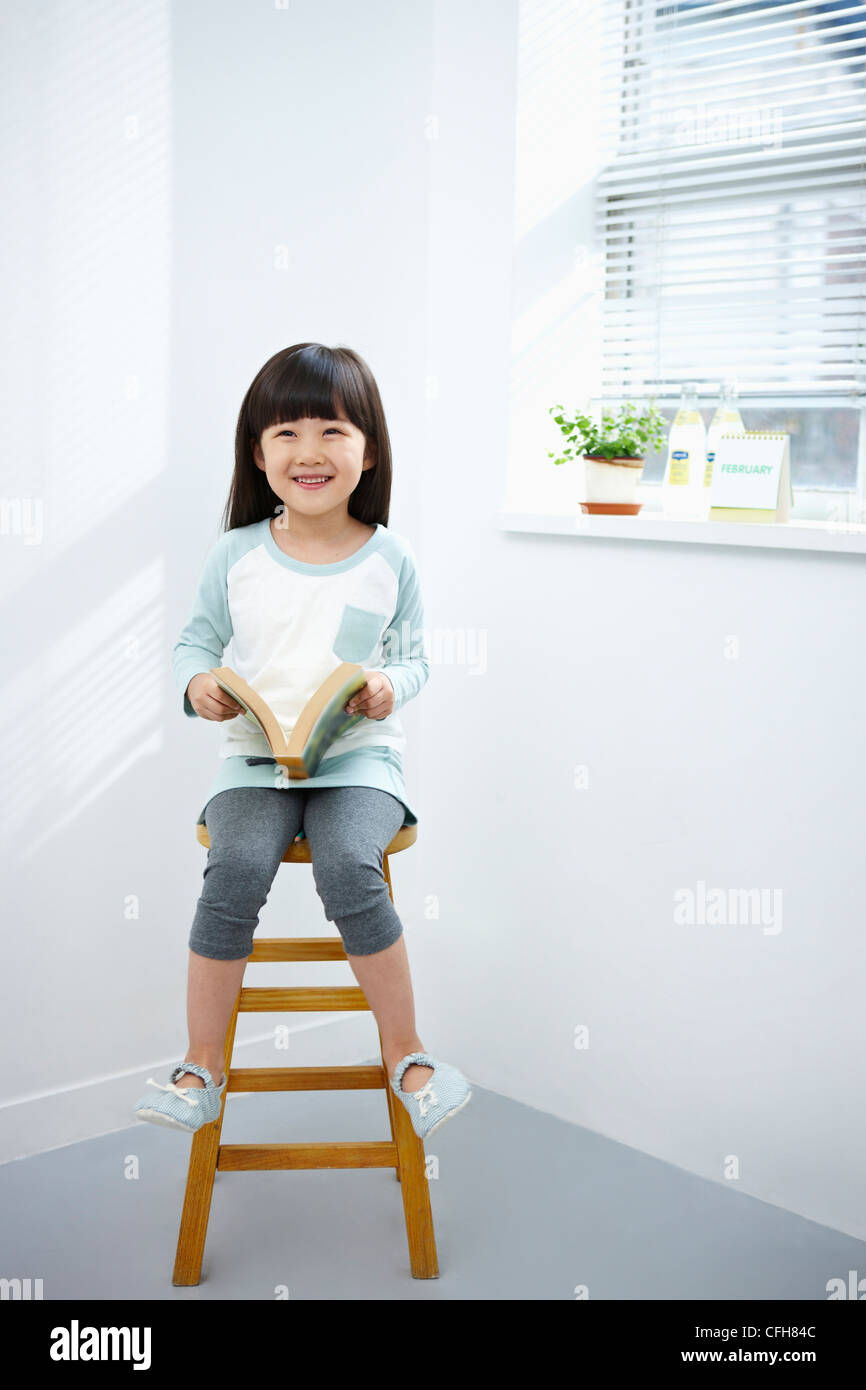 The girl holding a book on the chair Stock Photo - Alamy